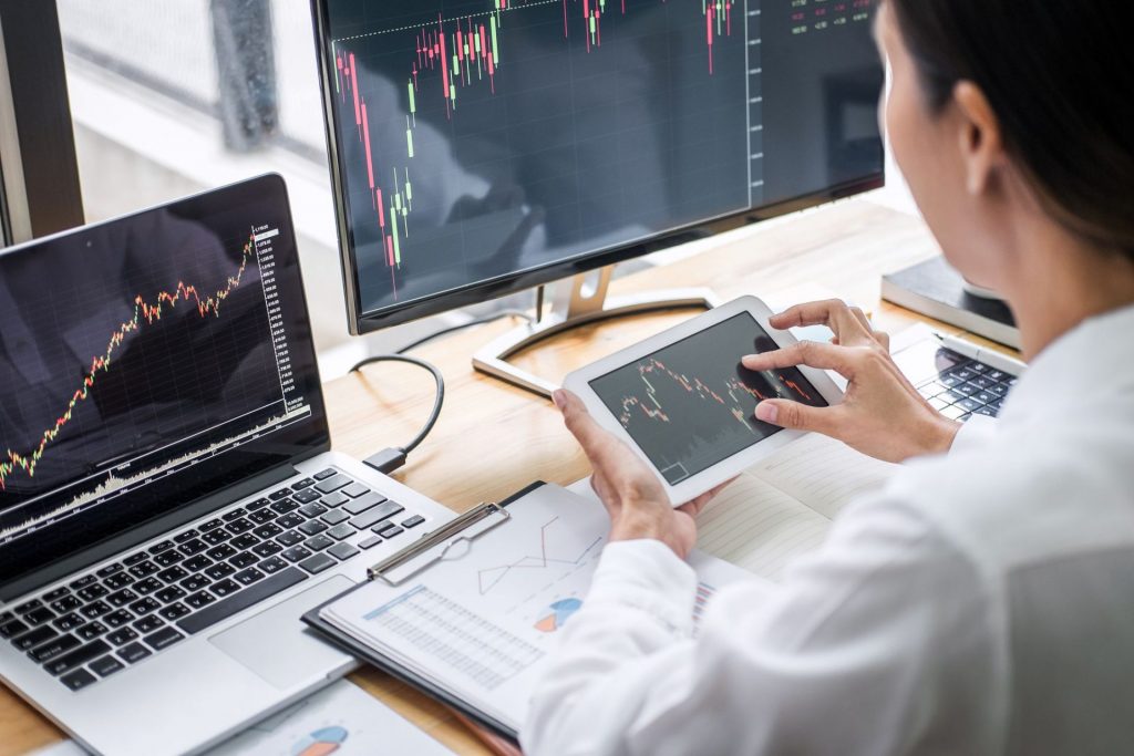 Lower-highs, lower-lows: imagem mostra um homem sentado, mexendo em seu celular, de frente para seu notebook e segunda tela onde mostram gráficos.